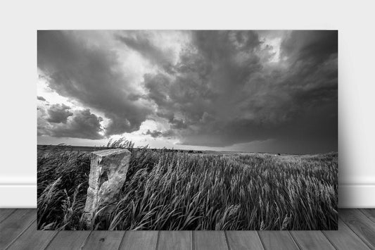 Western metal print of prairie grass surrounding an old stone marker as storms brew on the horizon on a stormy spring day in Kansas by Sean Ramsey of Southern Plains Photography.