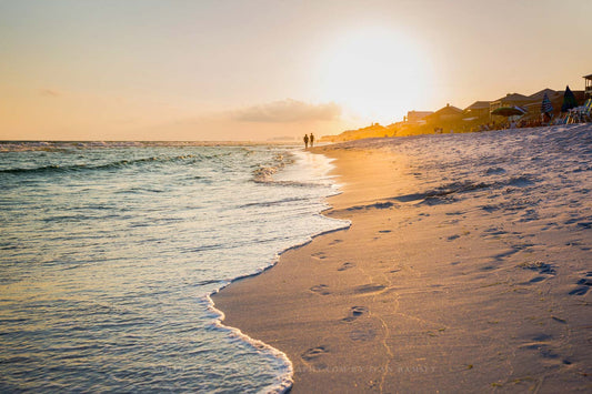 Coastal photography print of people walking along the beach leaving footprints as waves roll ashore at sunset along the Gulf Coast in Destin, Florida by Sean Ramsey of Southern Plains Photography.