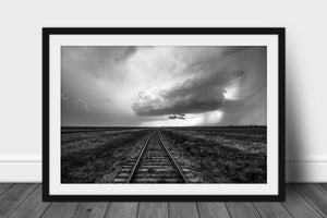 Framed and matted wanderlust print of railroad tracks leading to a distant storm cloud on a stormy spring day on the plains of Kansas in black and white by Sean Ramsey of Southern Plains Photography.
