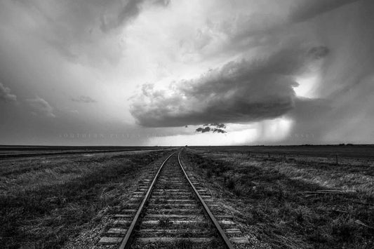 Black and white photography print of railroad tracks leading to a distant storm cloud on the horizon on a spring day on the plains of Kansas by Sean Ramsey of Southern Plains Photography.