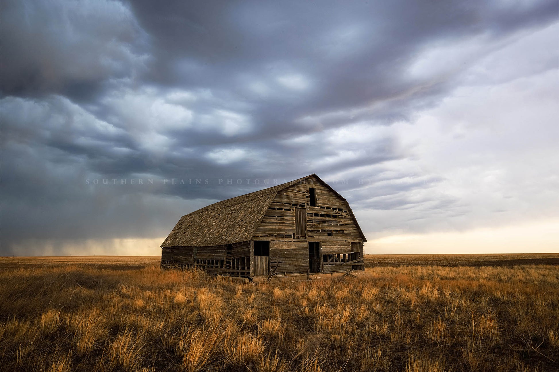 Great plains photography print of an old wooden barn standing alone in prairie grass under a stormy sky in Oklahoma by Sean Ramsey of Southern Plains Photography.