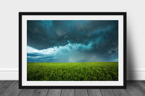 Framed storm print of a teal hued thunderstorm over a lush green wheat field on a stormy spring day in Kansas by Sean Ramsey of Southern Plains Photography.