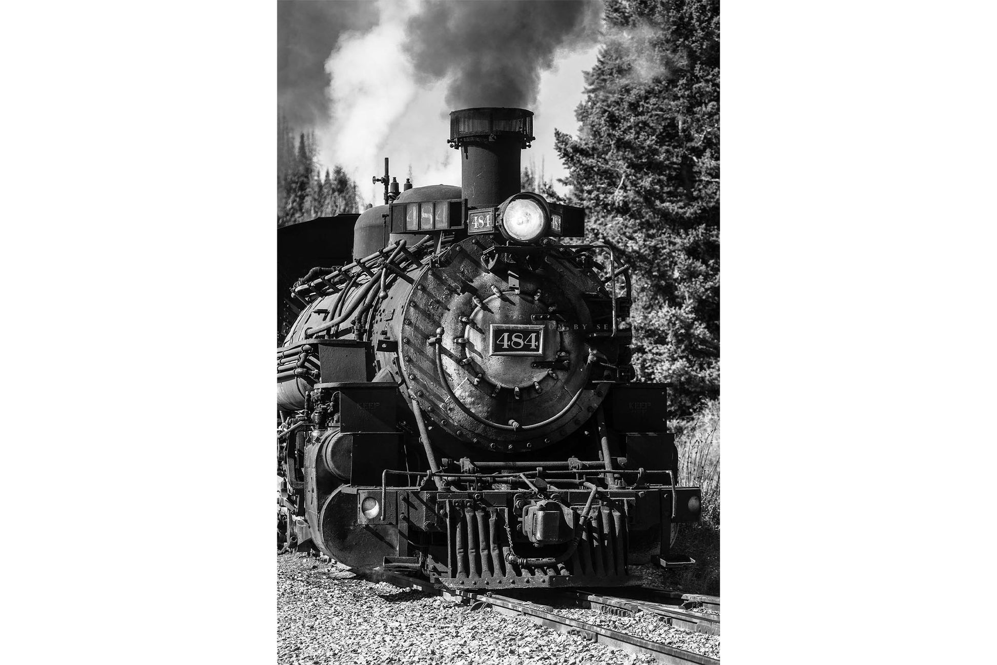Vertical black and white train photography print of a vintage style steam engine rolling down the tracks along a railroad in the mountains of Colorado by Sean Ramsey of Southern Plains Photography.
