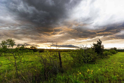 Country photography print of a stormy sky illuminated by sunlight over a barbed wire fence row on a spring evening in Texas by Sean Ramsey of Southern Plains Photography.