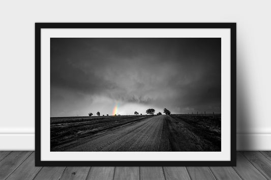 Framed and matted country print in color on black and white of a rainbow shining in a stormy sky as a dirt road leads to tree silhouettes on a spring day in Kansas by Sean Ramsey of Southern Plains Photography.