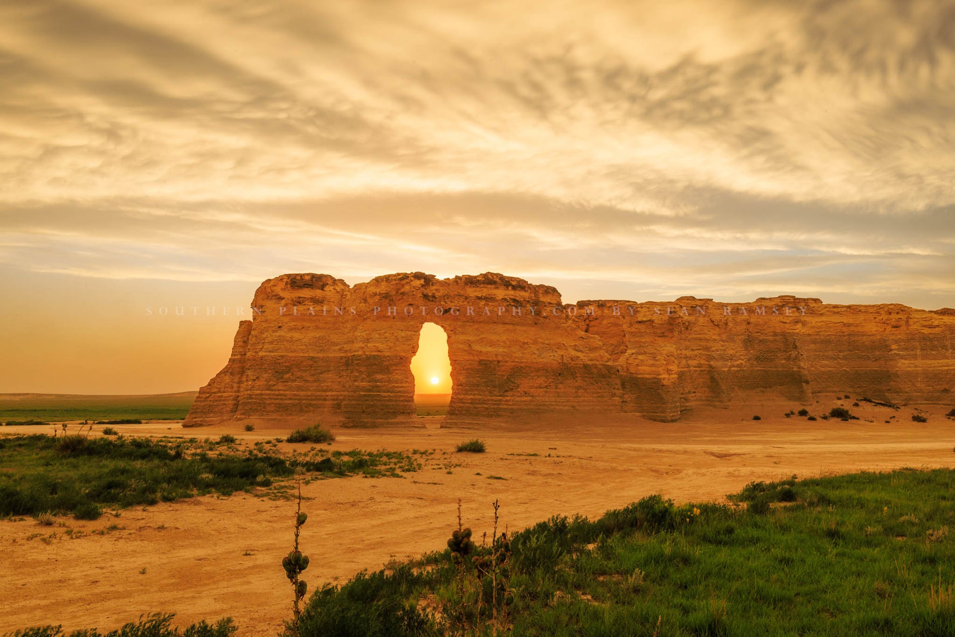 Great Plains photography print of the sun peeking through an opening in a chalk formation at sunset on a stormy evening at Monument Rocks in Gove County, Kansas by Sean Ramsey of Southern Plains Photography.