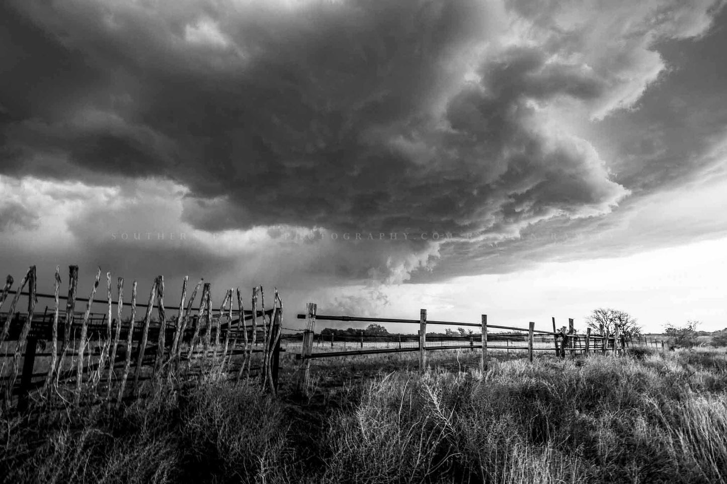 Black and white storm photography print of a thunderstorm advancing over an old rickety fence on a stormy spring day in Oklahoma by Sean Ramsey of Southern Plains Photography.