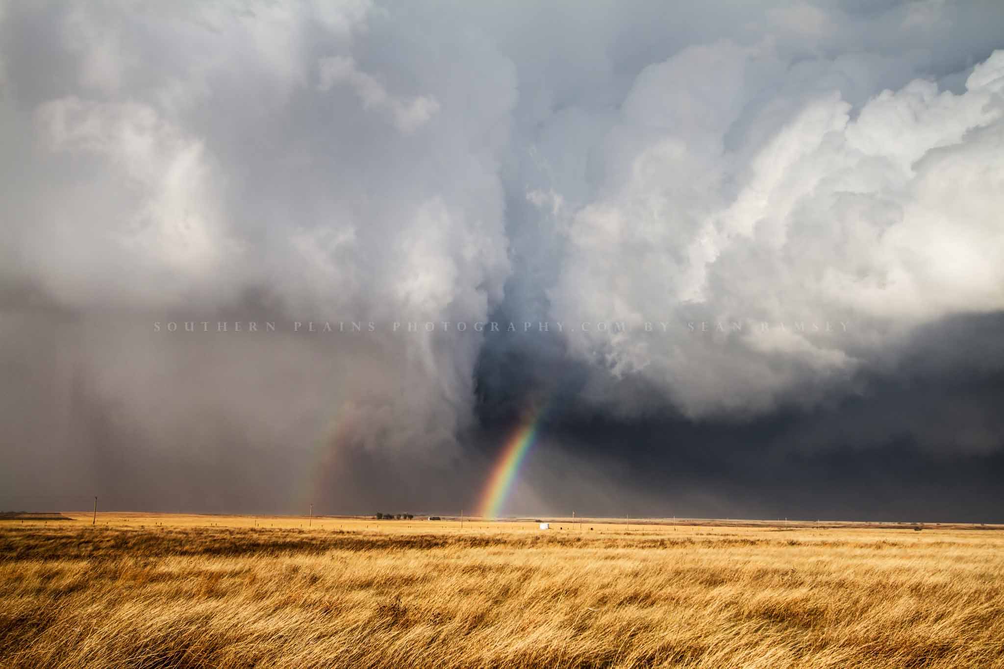 Great plains photography print of a rainbow between a rain wrapped tornado and storm cloud over golden prairie grass on a stormy spring day in Kansas by Sean Ramsey of Southern Plains Photography.
