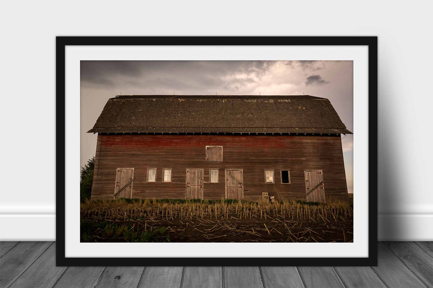 Framed country print wall art of an old red barn side with multiple doors on a stormy day in Nebraska by Sean Ramsey of Southern Plains Photography.