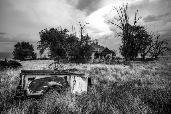 Black and white country photography print of a rusted pickup bed in the front yard of an abandoned house on a spring day in the Oklahoma Panhandle by Sean Ramsey of Southern Plains Photography.