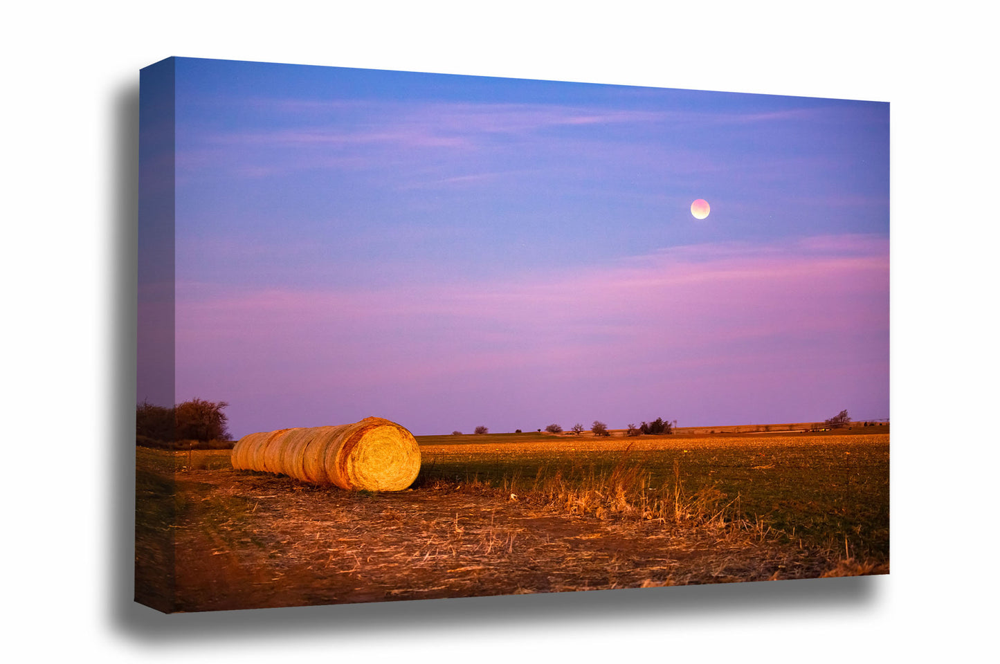 Celestial canvas wall art of round hay bales under a blood moon during a lunar eclipse at sunrise in Oklahoma by Sean Ramsey of Southern Plains Photography.
