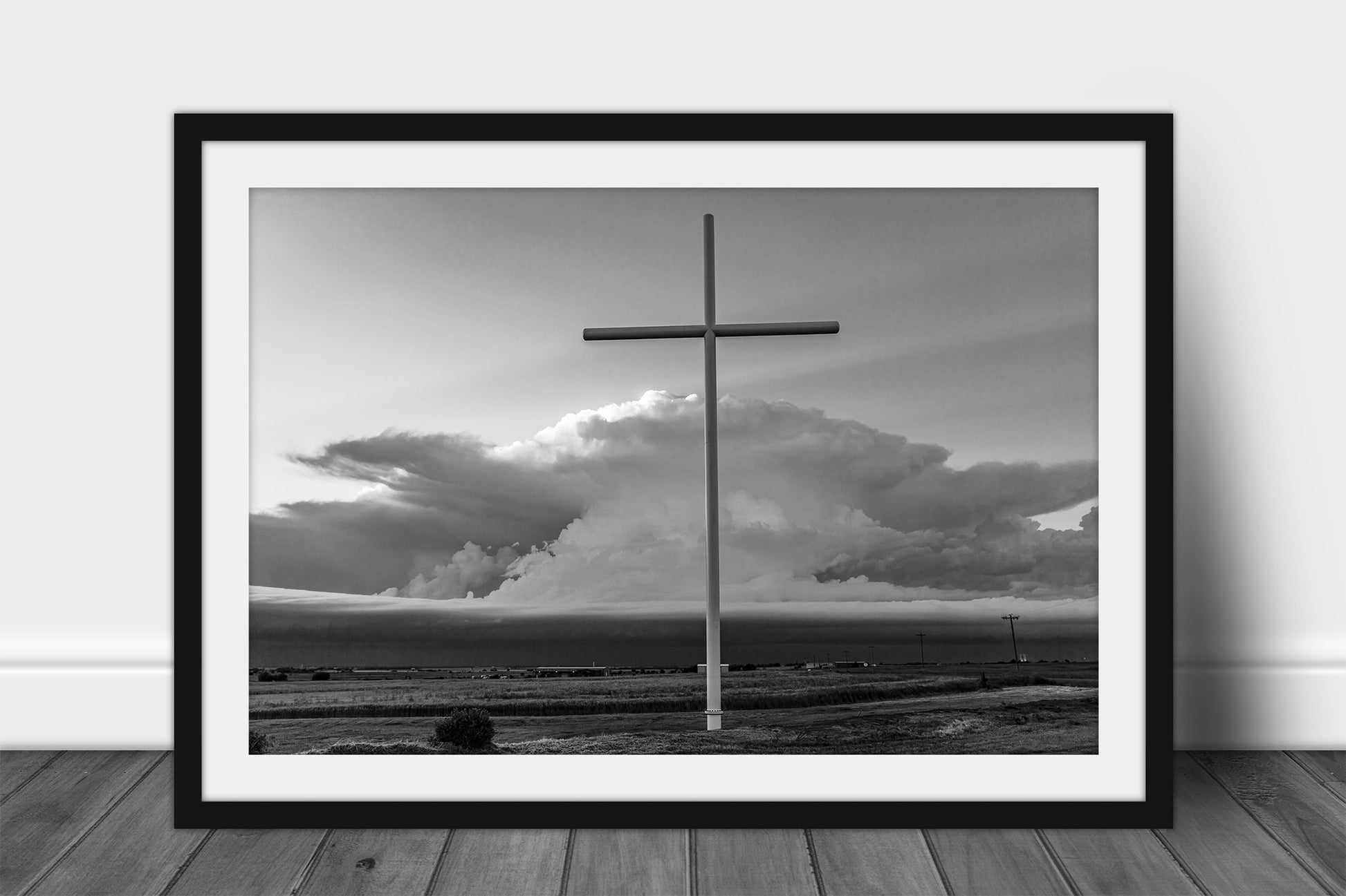 Framed and matted spiritual print in black and white of a large cross in front of a supercell thunderstorm on a stormy day in Oklahoma by Sean Ramsey of Southern Plains Photography.