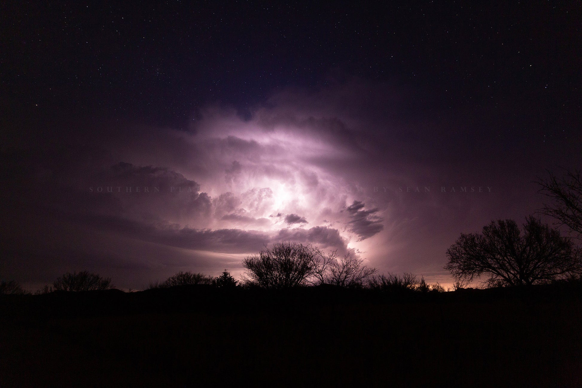 Storm photography print of a thunderstorm illuminated by lightning while stars twinkle above on a stormy night in Oklahoma by Sean Ramsey of Southern Plains Photography.