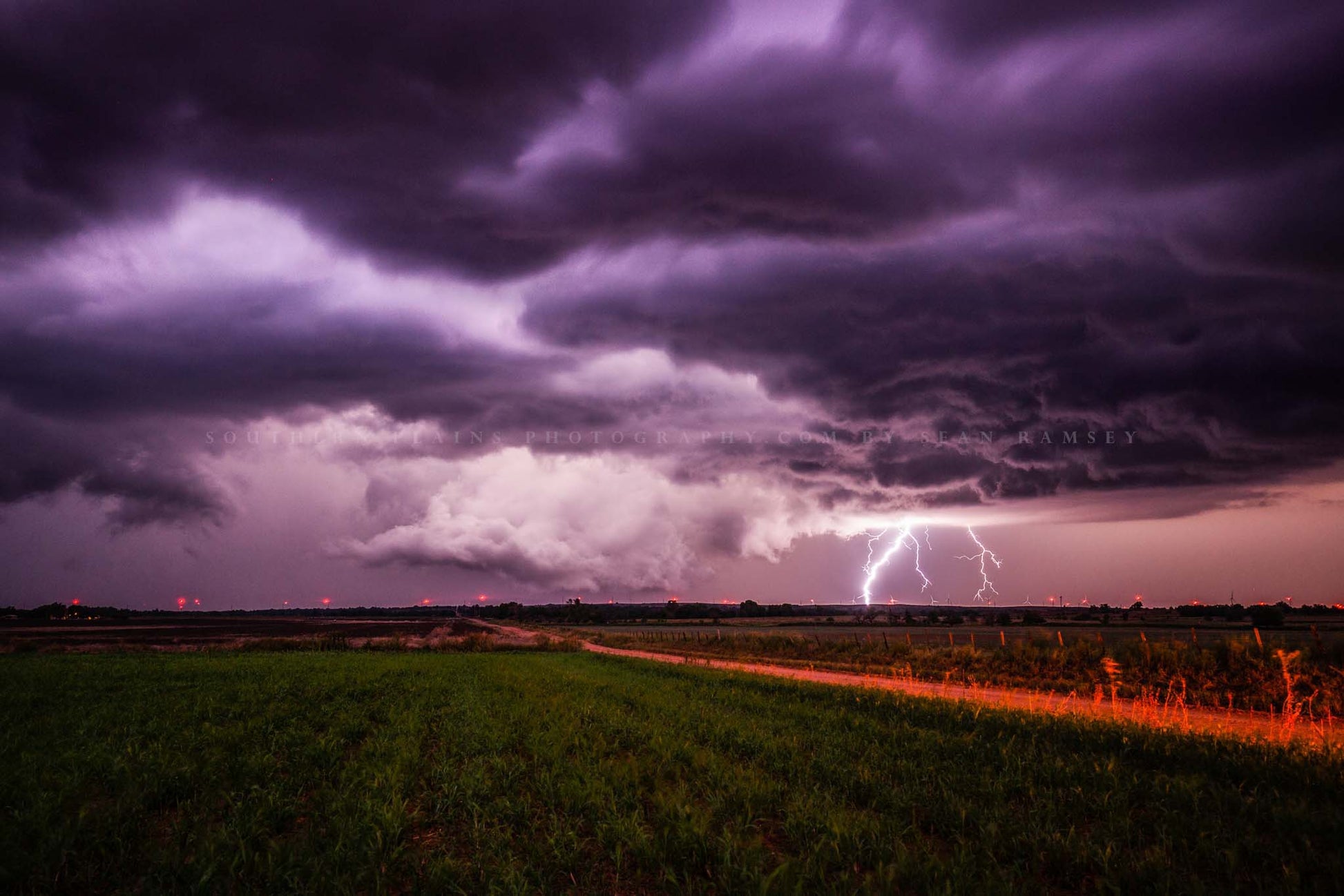 Storm photography print of a distant lightning strike as a thunderstorm advances over a field after dark on a stormy night in Kansas by Sean Ramsey of Southern Plains Photography.