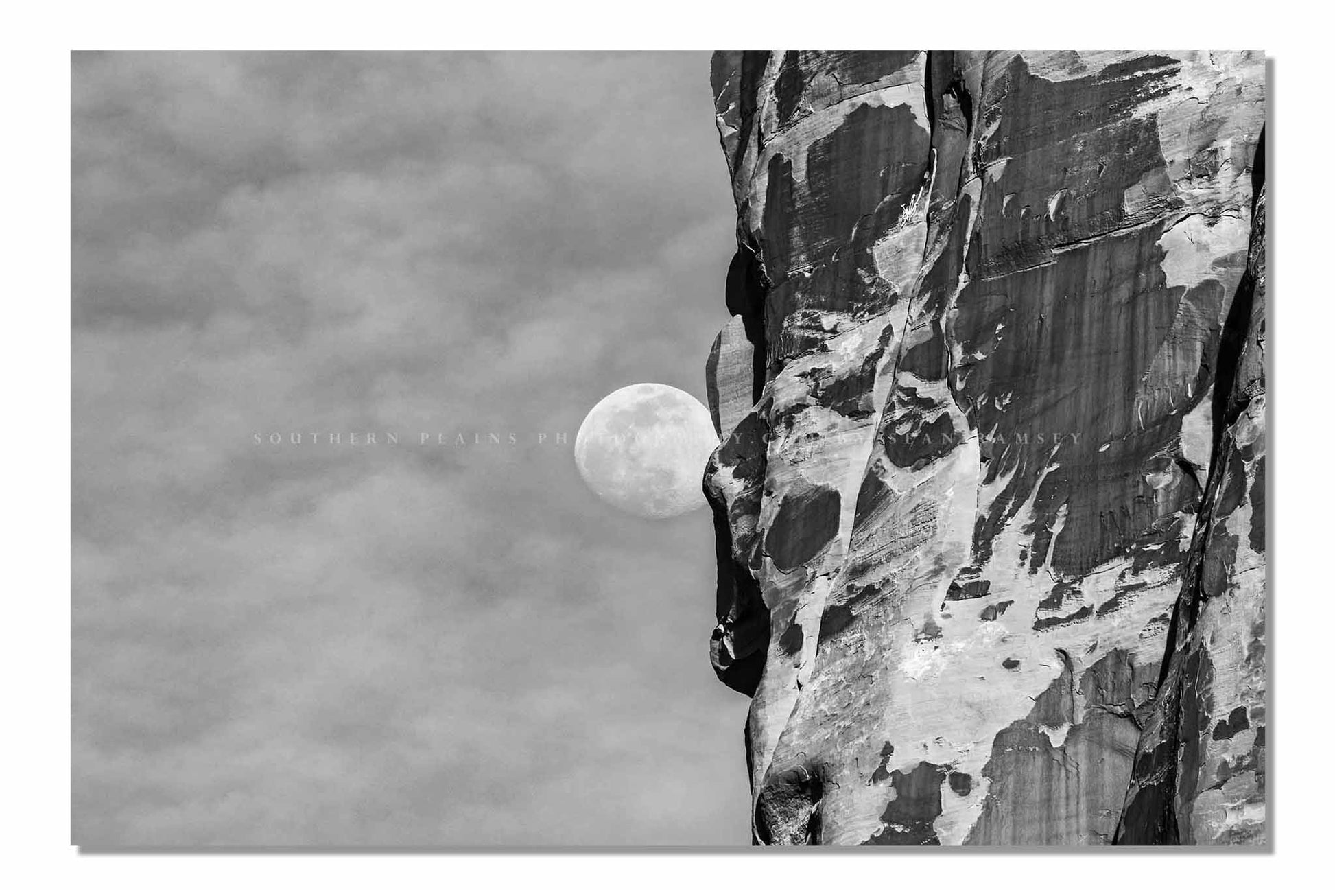 Black and white Southwest photography print of a Waning Gibbous Moon beside a sandstone cliff in Arches National Park, Utah by Sean Ramsey of Southern Plains Photography.