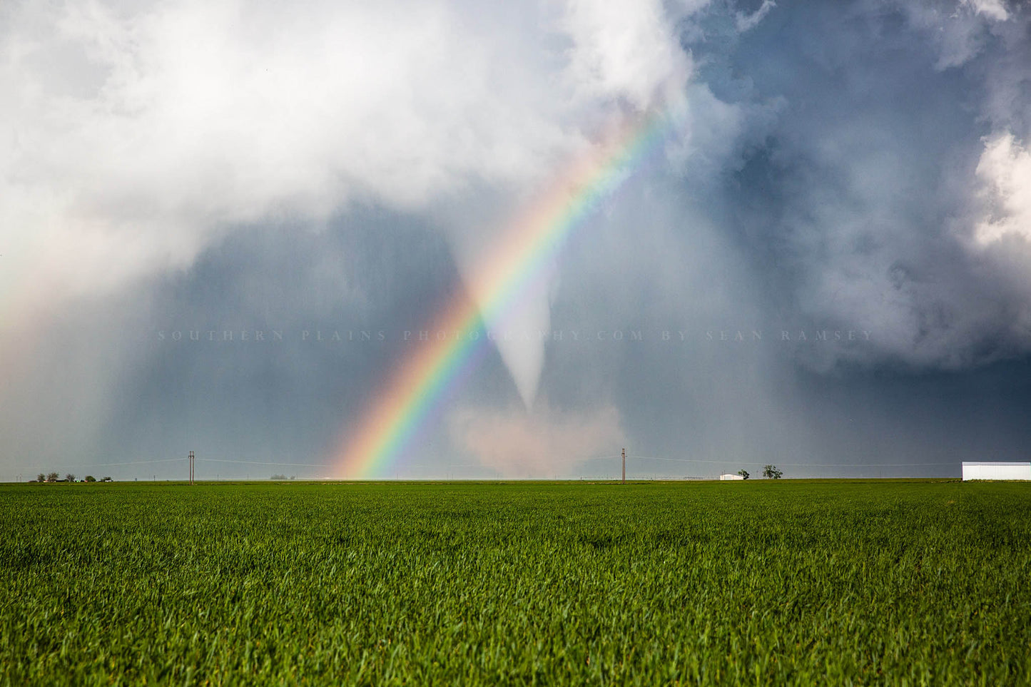 Storm photography print of a white tornado passing through a rainbow as it spins up dust in a field on a stormy spring day in Texas by Sean Ramsey of Southern Plains Photography.