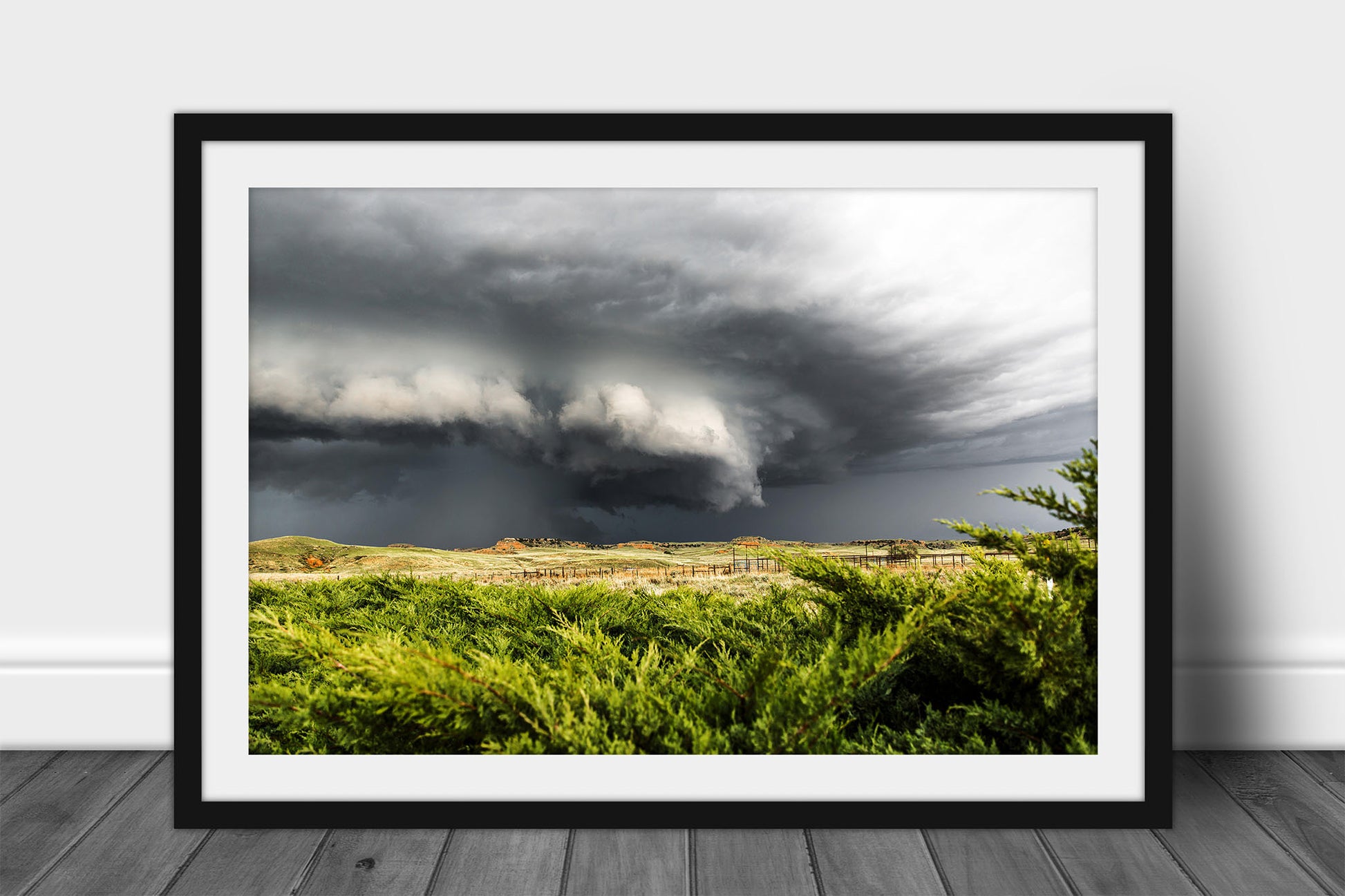 Framed and matted storm print of a supercell thunderstorm advancing over cedar bushes on a stormy spring day on the Nebraska prairie by Sean Ramsey of Southern Plains Photography.