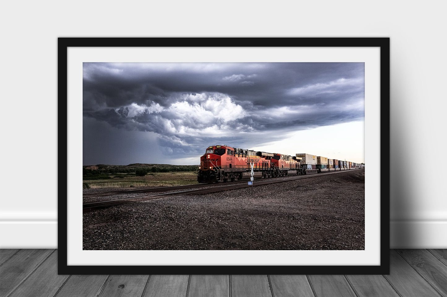 Framed and matted train print of a locomotive rolling through a rural intersection and storm clouds churn above on a stormy spring day in Texas by Sean Ramsey of Southern Plains Photography.
