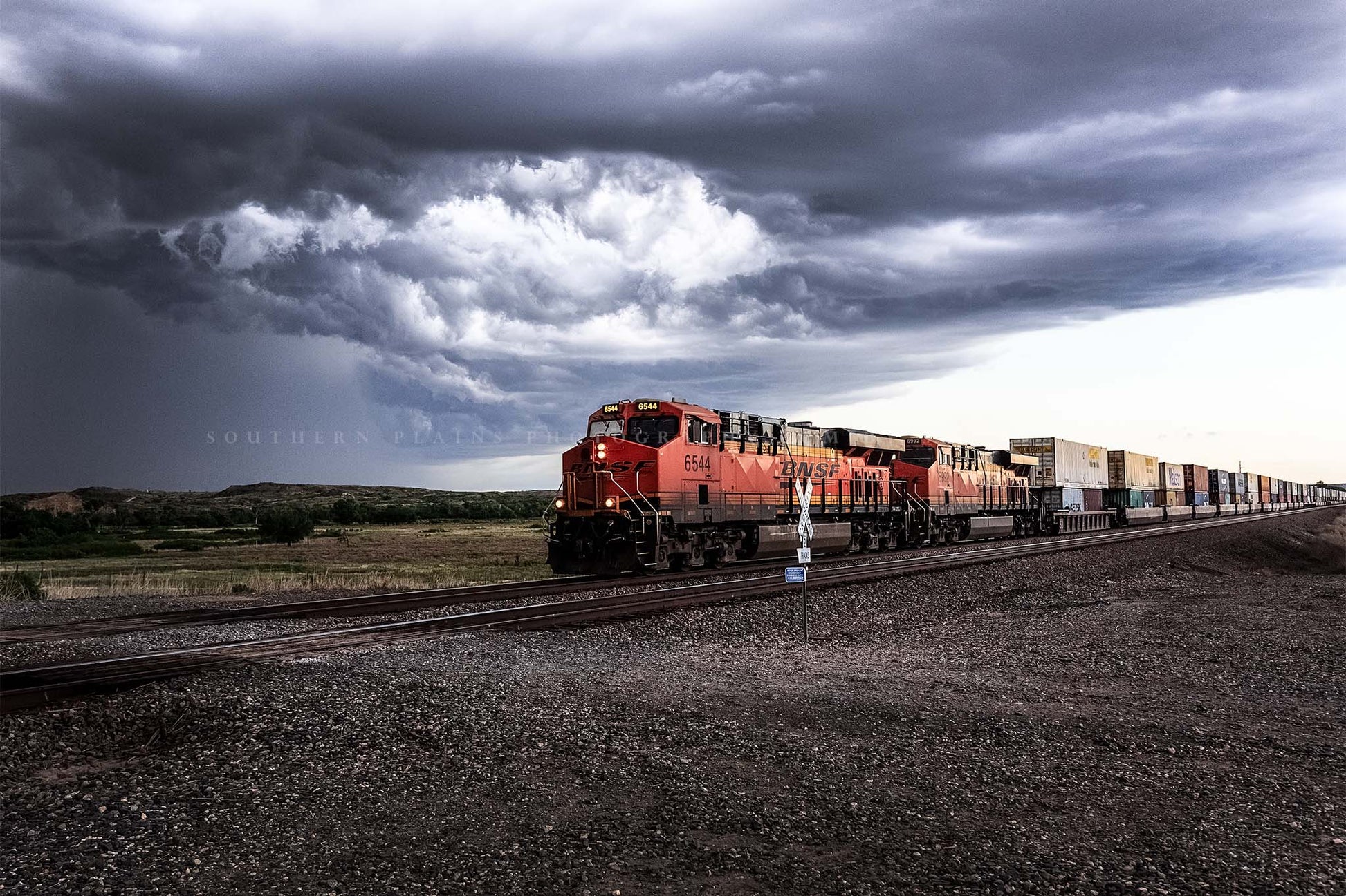 Train photography print of a locomotive rolling through a rural intersection and storm clouds churn above on a stormy spring day in Texas by Sean Ramsey of Southern Plains Photography.