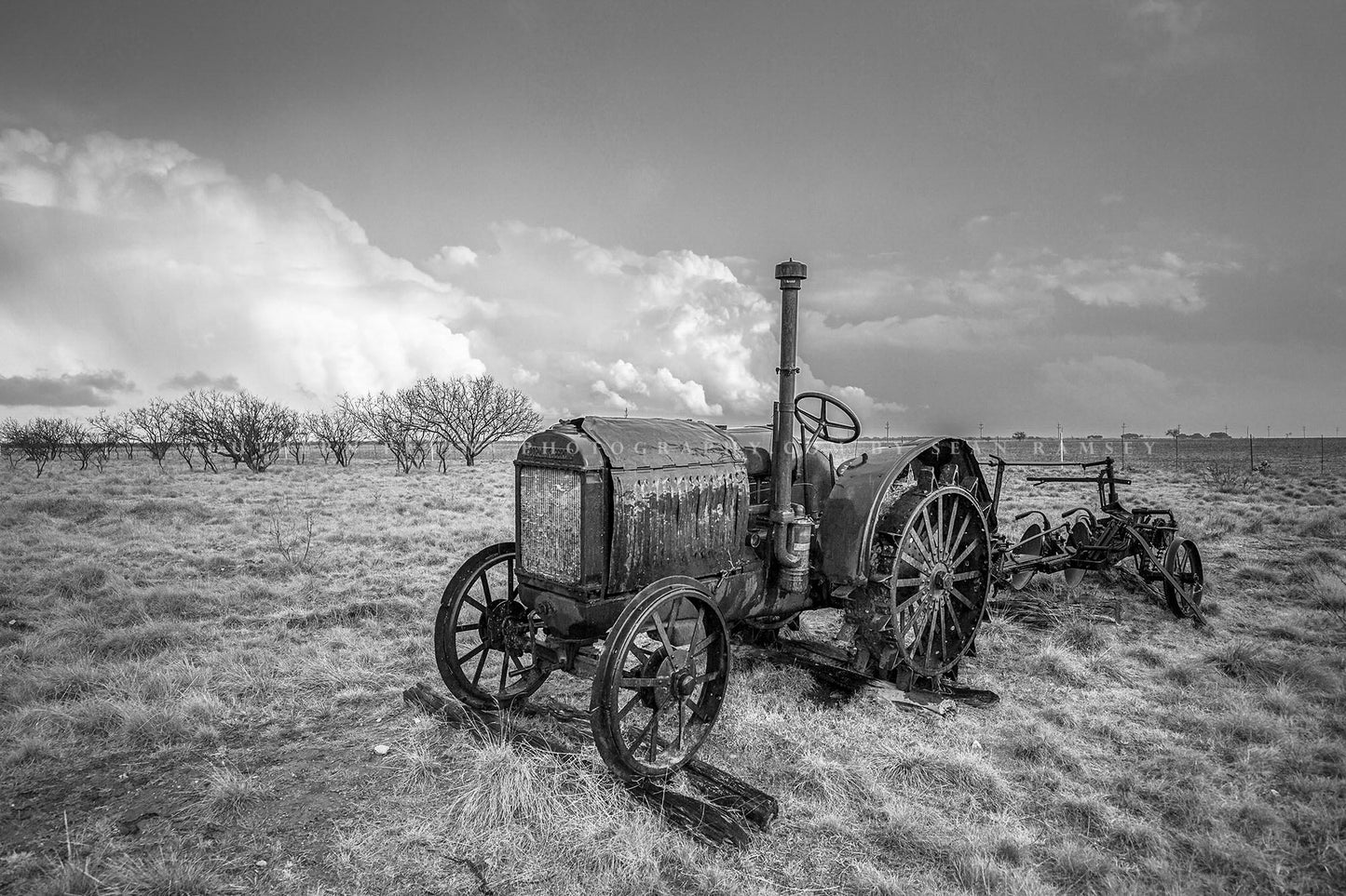 Black and white country photography print of a classic McCormick-Deering tractor sitting in a field on a stormy spring day in Texas by Sean Ramsey of Southern Plains Photography.
