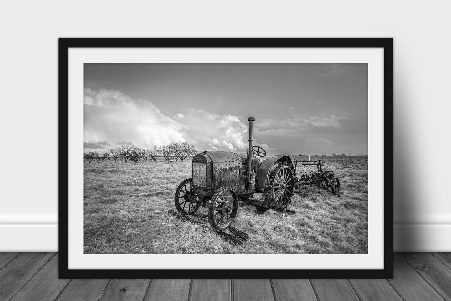 Framed and matted black and white photography print of a rustic McCormick-Deering tractor in a field on a stormy day in Texas by Sean Ramsey of Southern Plains Photography.
