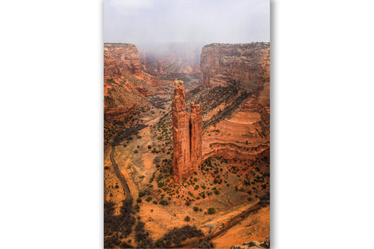 Vertical western landscape photography print of Spider Rock rising from the canyon floor as a snow squall passes through Canyon de Chelly on a late winter day in Arizona by Sean Ramsey of Southern Plains Photography.