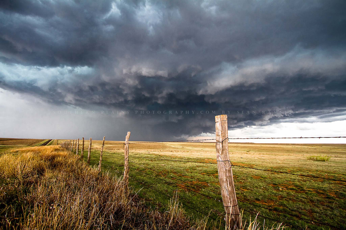 Storm photography print of a powerful thunderstorm with a gentle appearance over a barbed wire fence on a stormy spring day in Texas by Sean Ramsey of Southern Plains Photography.