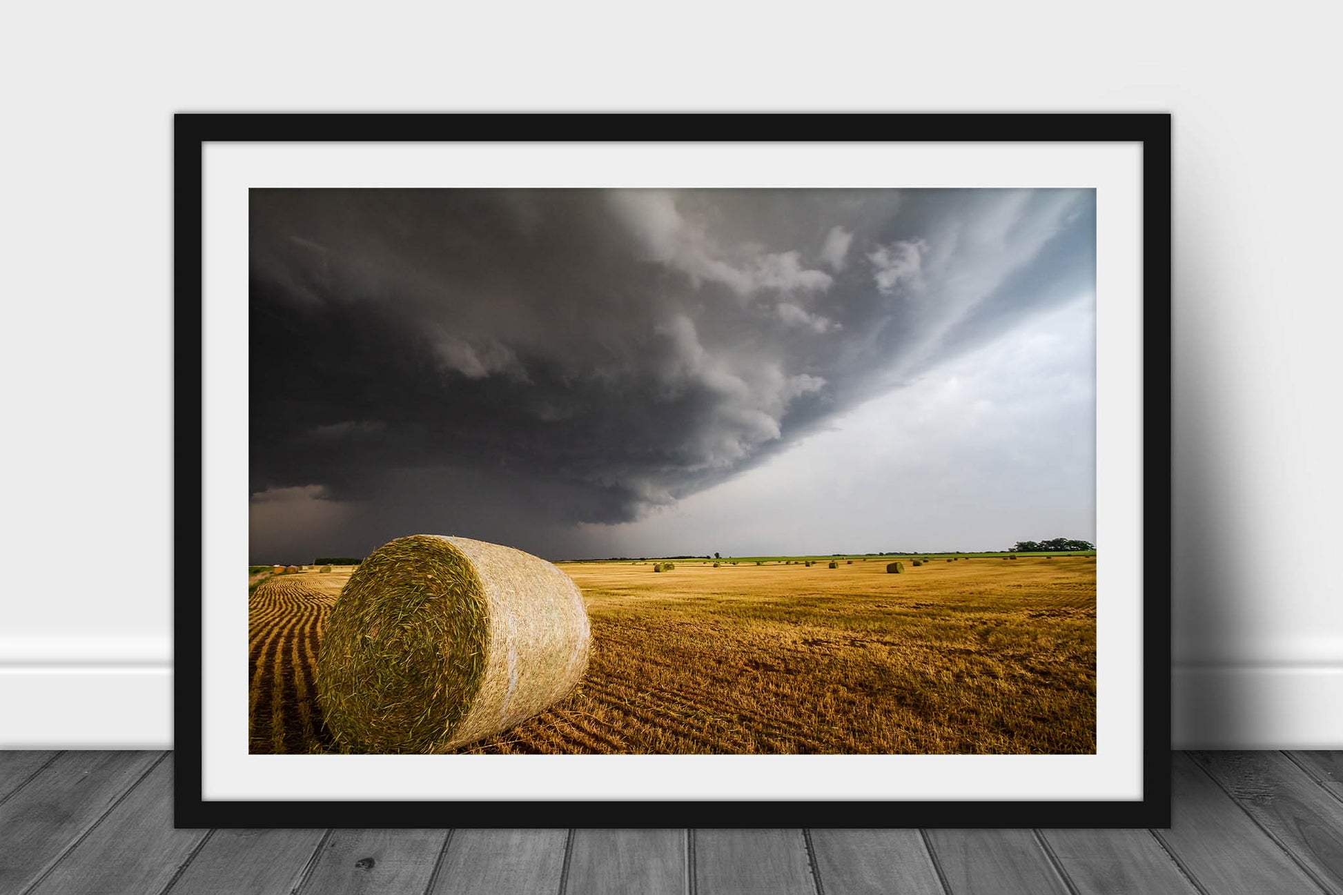 Framed country print with optional mat of a storm advancing over a golden round hay bale on a stormy spring day in Kansas by Sean Ramsey of Southern Plains Photography.