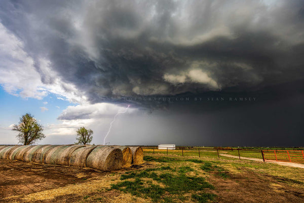 Storm photography print of thunderstorm with lightning strike over round hay bales on a stormy spring day in Oklahoma by Sean Ramsey of Southern Plains Photography.
