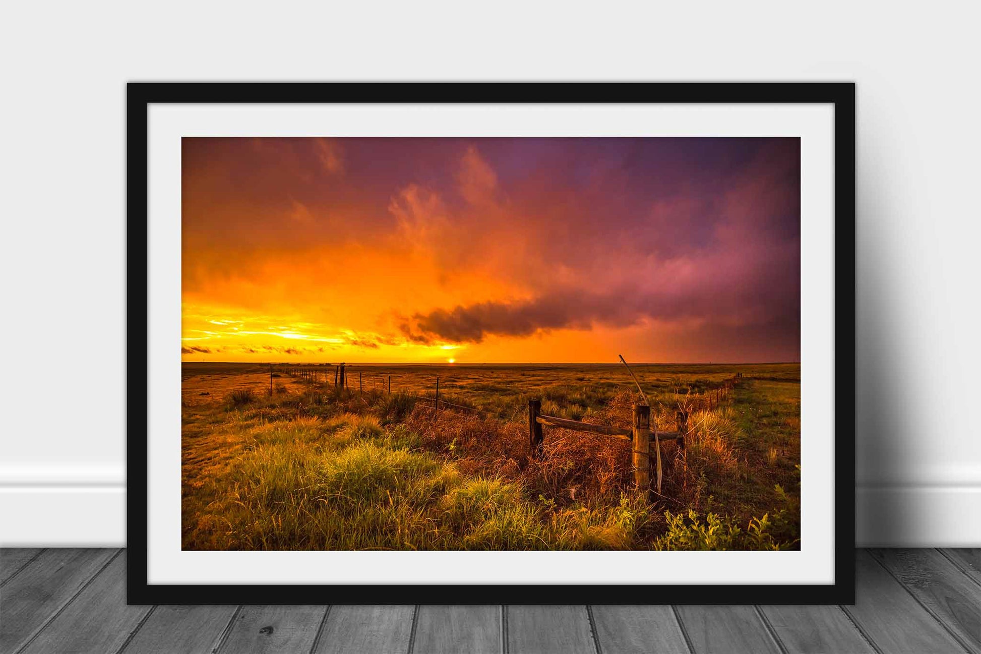 Framed and matted Great Plains print of a warm sunset with a stormy sky taking place over a prairie framed by a barbed wire fence in the Oklahoma panhandle by Sean Ramsey of Southern Plains Photography.