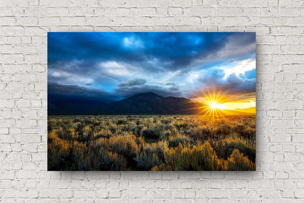 High desert landscape metal print wall art of the sun twinkling behind Taos Mountain as storm clouds move through over sagebrush on an autumn morning near Taos, New Mexico by Sean Ramsey of Southern Plains Photography.