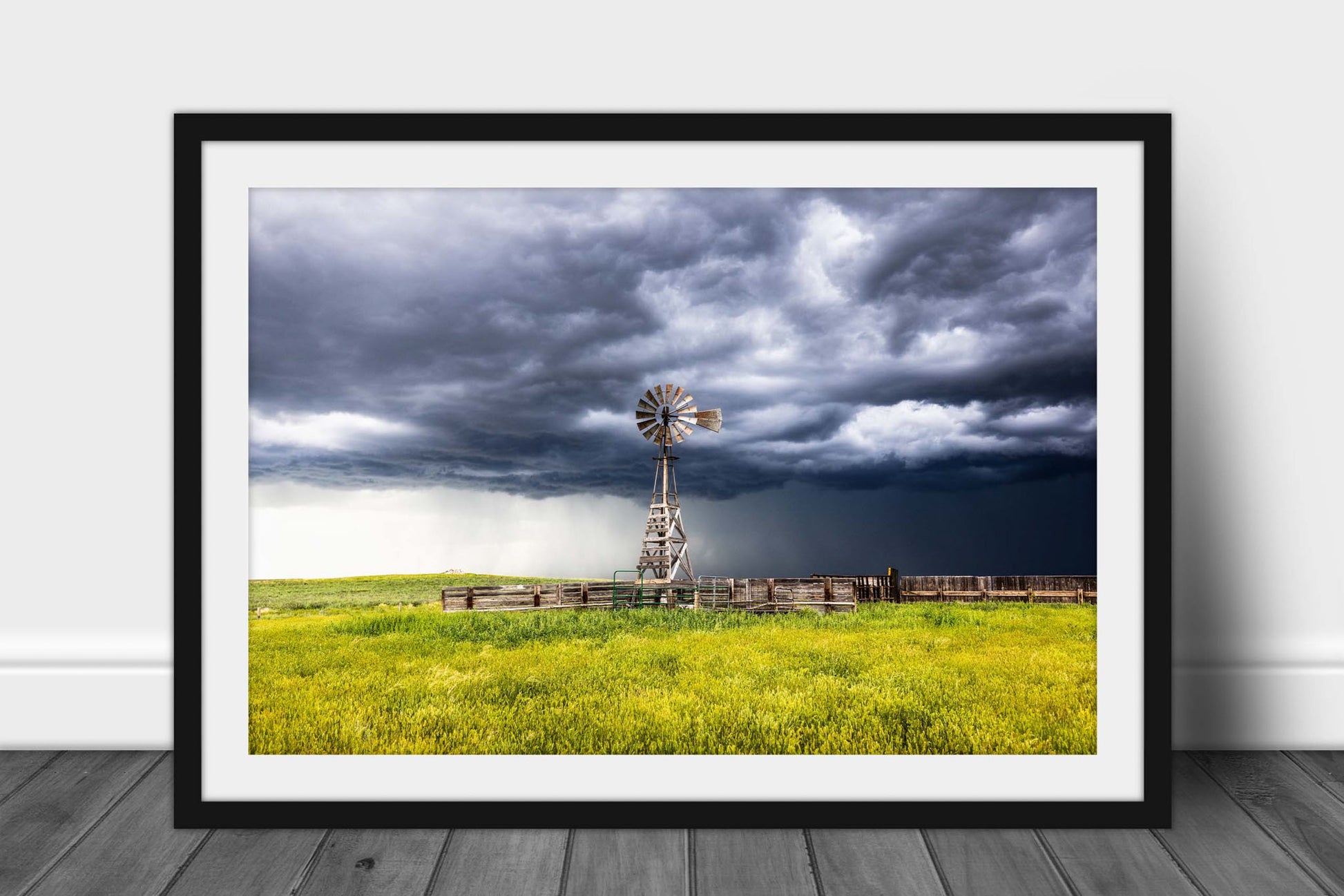 Framed and matted western print of a storm advancing over an old windmill and cattle pens on a stormy spring day on the plains of Wyoming by Sean Ramsey of Southern Plains Photography.