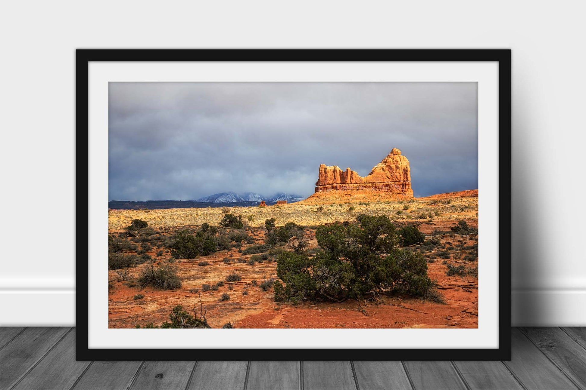 Southwest landscape framed print of a sandstone rock formation overlooking the desert as the snowy La Sal Mountains appear in the distance in Arches National Park near Moab, Utah by Sean Ramsey of Southern Plains Photography.