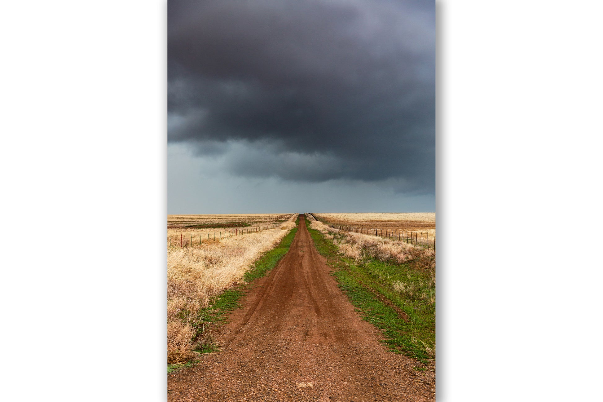 Vertical country photography print of a dirt road leading to a stormy sky on the horizon on a spring day on the plains of Texas by Sean Ramsey of Southern Plains Photography.