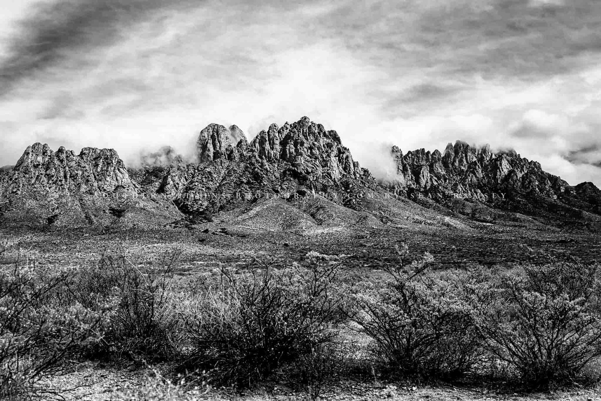 Black and white landscape photography print of the Organ Mountains rising from the Chihuahuan Desert floor as clouds roll over the peaks near Las Cruces, New Mexico by Sean Ramsey of Southern Plains Photography.