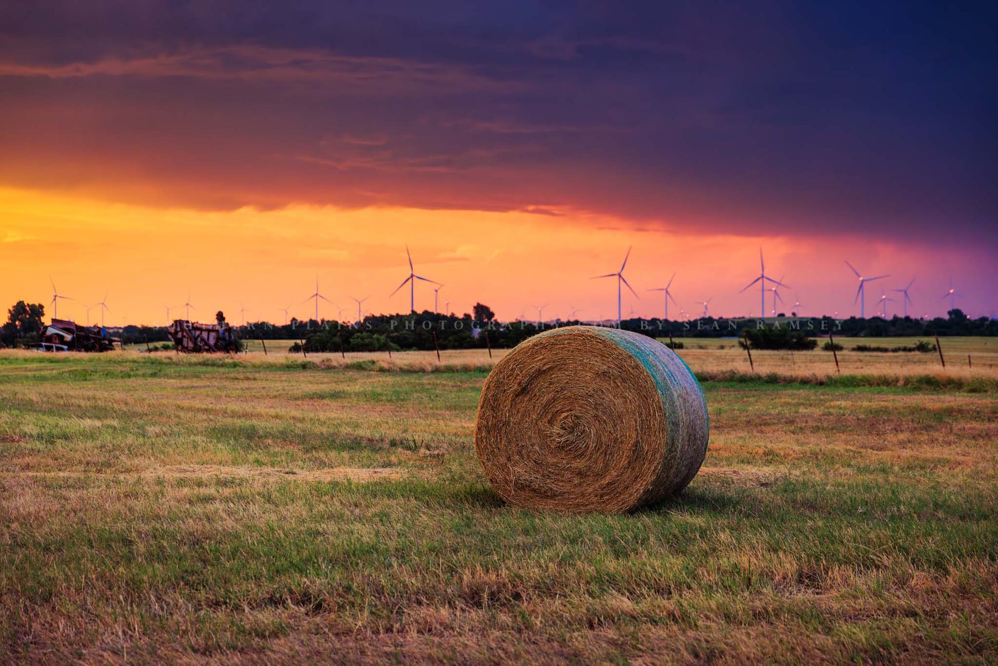 Farm and country photography print of a round hay bale sitting in a field as a stormy sunset takes place on a spring evening in Oklahoma by Sean Ramsey of Southern Plains Photography.