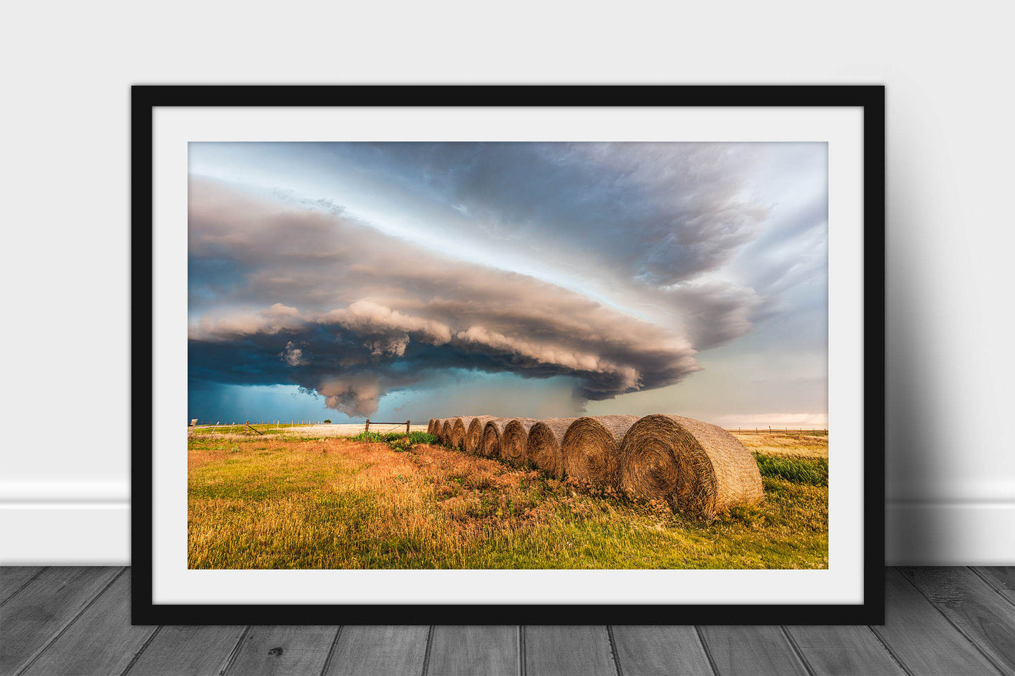 Framed and matted storm print of a massive supercell thunderstorm shelf cloud advancing over a row of hay bales on a stormy day on the plains of Oklahoma by Sean Ramsey of Southern Plains Photography.