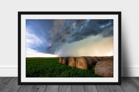 Framed and matted storm print of a thunderstorm advancing over round hay bales on a stormy summer day in Kansas by Sean Ramsey of Southern Plains Photography.