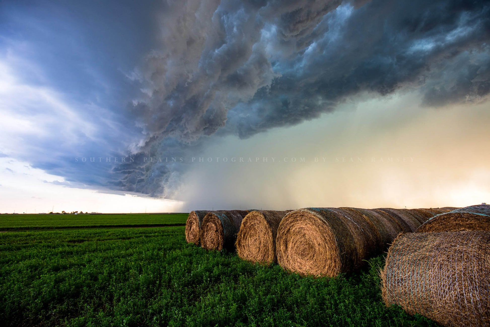 Country photography print of a powerful thunderstorm advancing over round hay bales on a stormy autumn day in Kansas by Sean Ramsey of Southern Plains Photography.