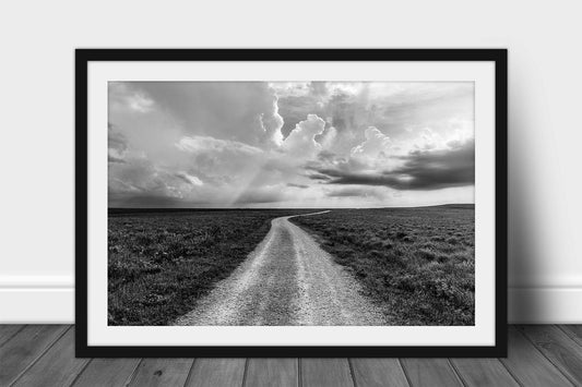 Framed and matted Great Plains print in black and white of a dirt road passing through the Tallgrass prairie as storm clouds build on the horizon in the Flint Hills of Kansas by Sean Ramsey of Southern Plains Photography.