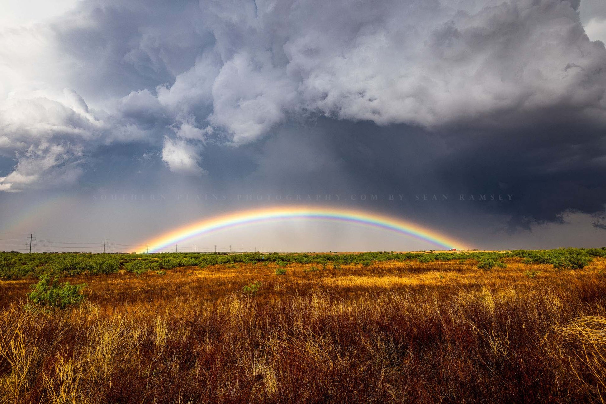 Landscape photography print of a brilliant rainbow low on the horizon under a stormy sky on a spring day in Texas by Sean Ramsey of Southern Plains Photography.