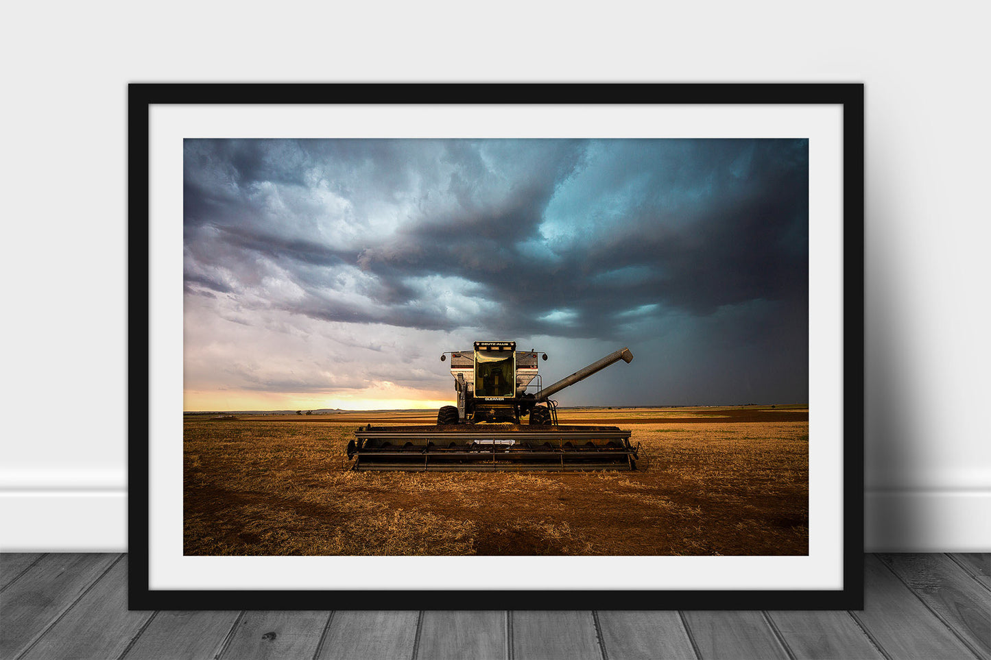 Framed and matted farm wall art of a combine swather sitting in a field under storm clouds on a stormy day in Oklahoma by Sean Ramsey of Southern Plains Photography.