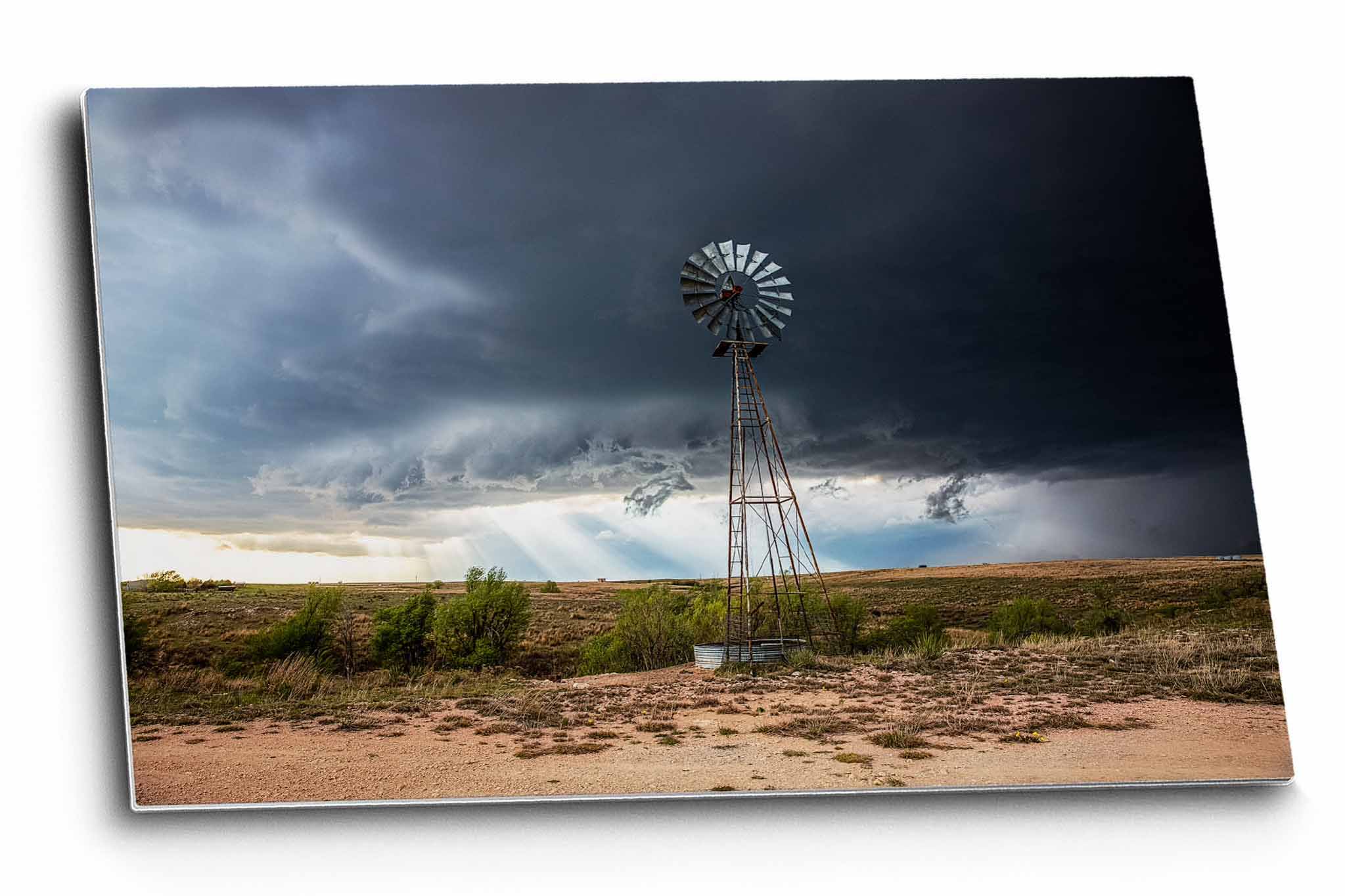 Country aluminum metal print wall art of sunbeams breaking through an intense storm as an Aermotor windmill stands tall over the prairie landscape on a spring day in Texas by Sean Ramsey of Southern Plains Photography.