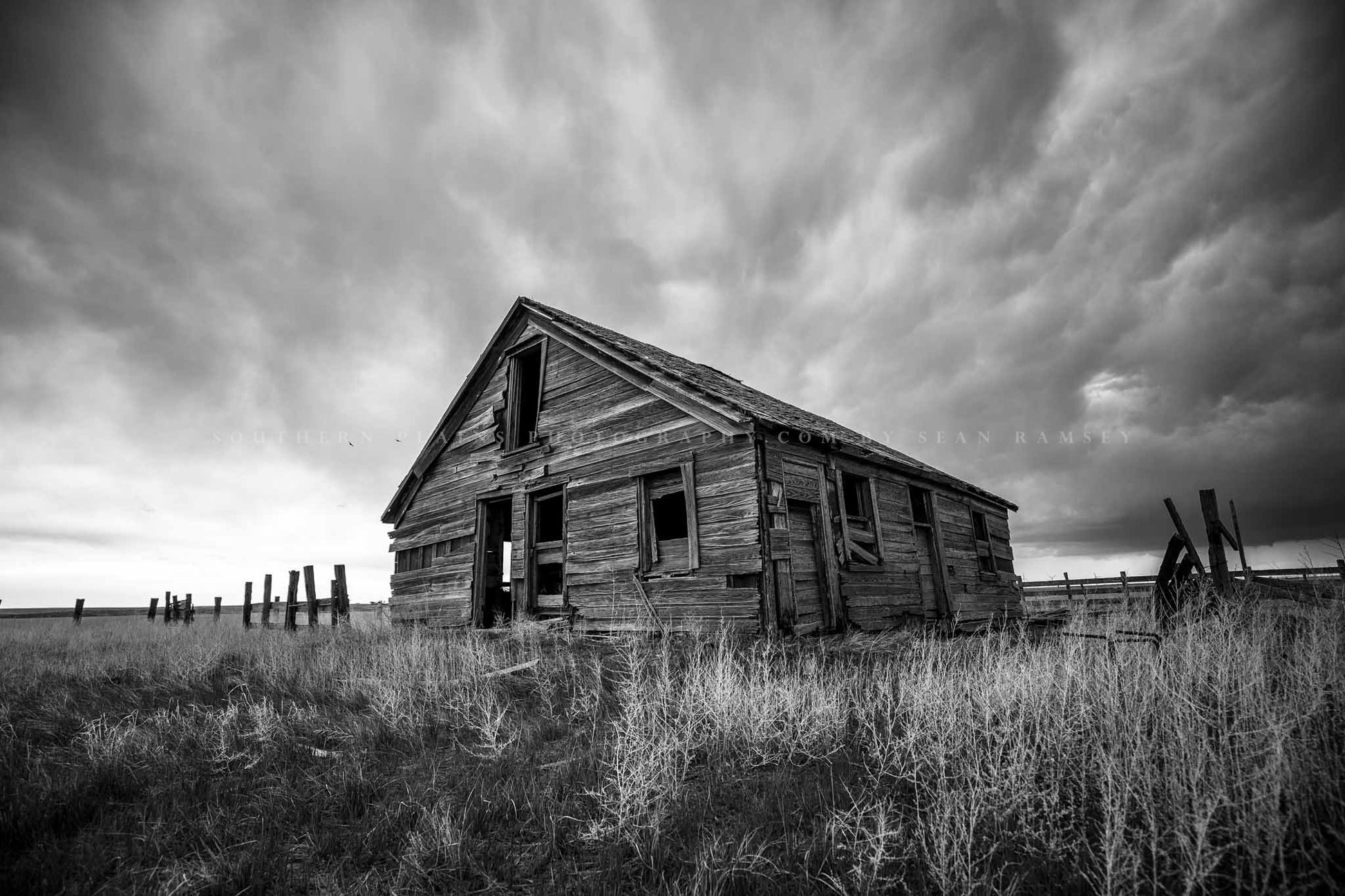 Rustic black and white photography print of an old abandoned homestead under a stormy sky on the plains of Colorado by Sean Ramsey of Southern Plains Photography.