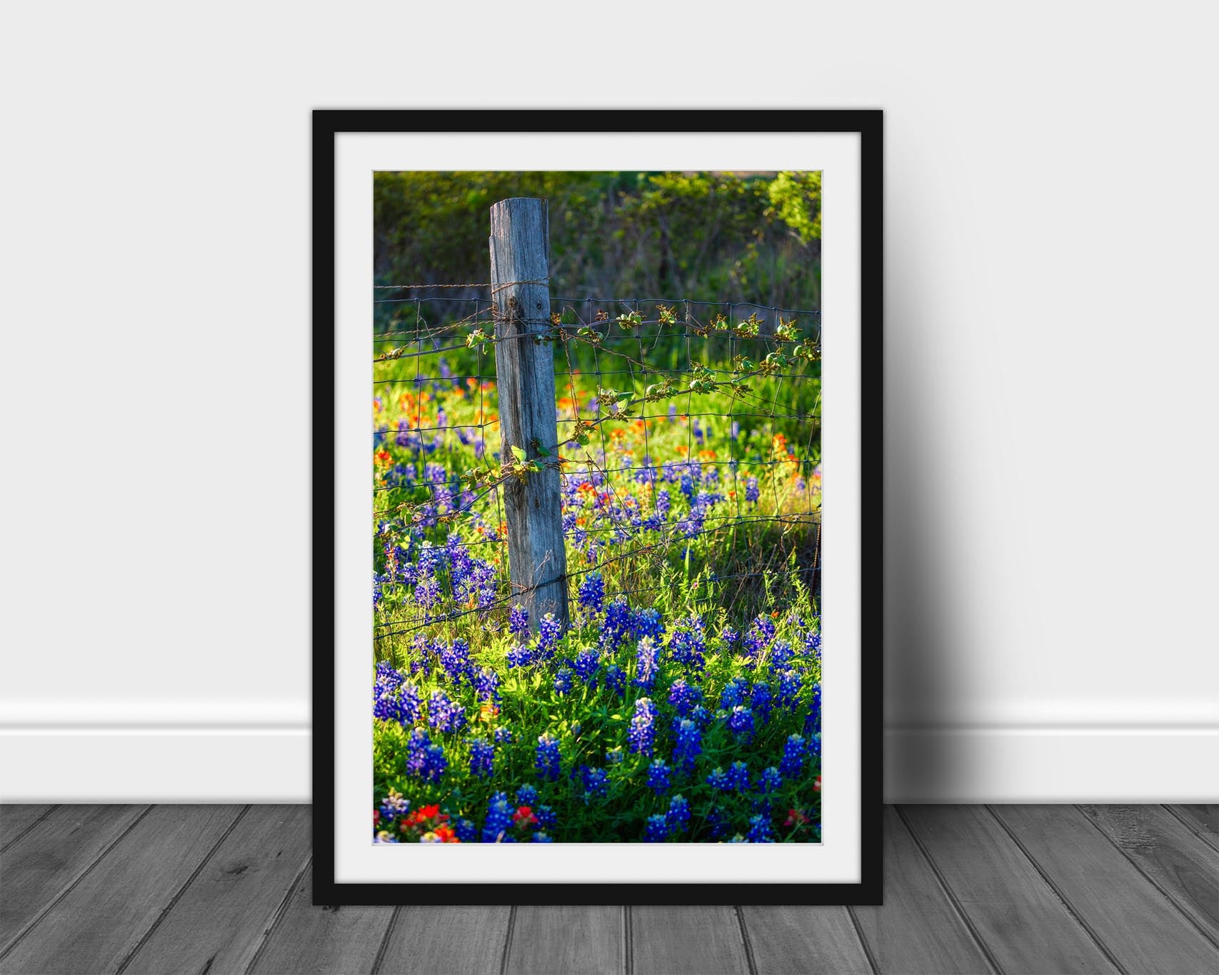 Vertical framed and matted country print of a fence post surrounded by bluebonnets and Indian paintbrush wildflowers on a spring day in Texas by Sean Ramsey of Southern Plains Photography.