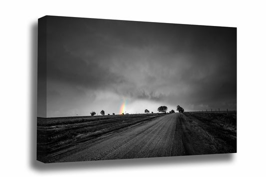 Whimsical canvas wall art of a dirt road leading to a colorful rainbow and tree silhouettes against a stormy sky in black and white on a spring day in Kansas by Sean Ramsey of Southern Plains Photography.