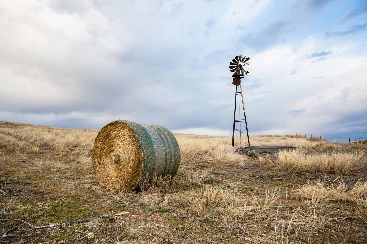 Country photography print of an old windmill and round hay bale on an autumn day on the Oklahoma prairie by Sean Ramsey of Southern Plains Photography.