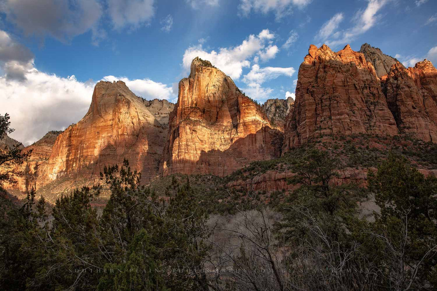 Sunlight breaks through clouds and shines on the Three Patriarchs in Zion National Park, Utah by Sean Ramsey of Southern Plains Photography.